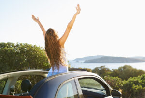 Picture of a woman with arms stretched out a convertible